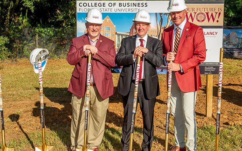 photo of three men in construction hats leaning on shovels and smiling