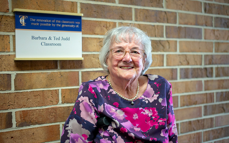 Barbara Judd in front of the Barbara and Ted Judd Theatre Classroom at Tallahassee Community College.