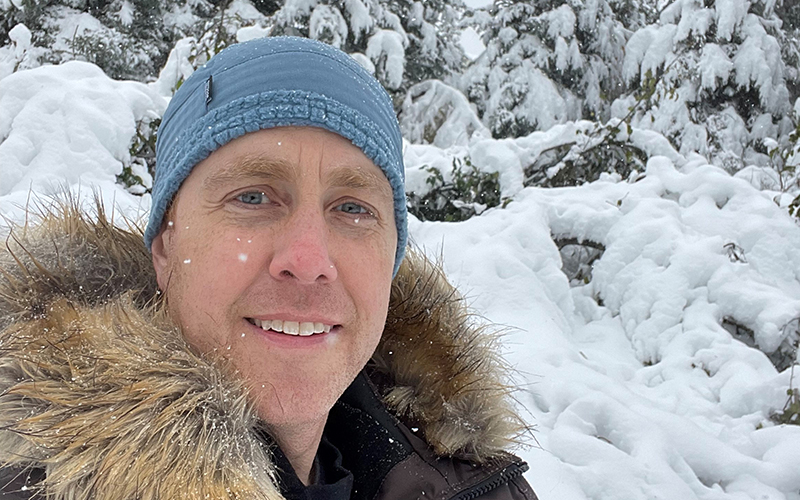 Smiling man wearing ski cap and coat in snowy landscape