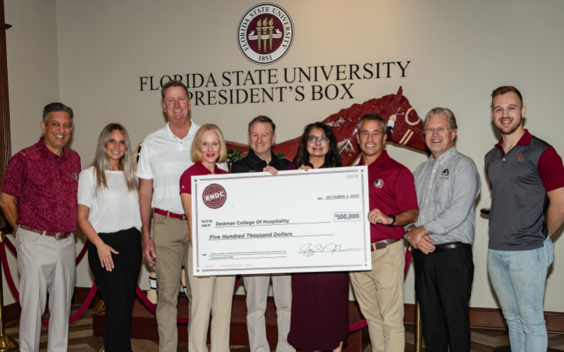 Image of Andy A. Jhanji, Interim Vice President for University Advancement; Amanda Manning, Hospitality and Tourism senior; Jay Johnson (’87), Region President, RNDC West; Jenn Engel (’97), Senior Vice President National Accounts, RNDC; FSU President Richard McCullough; FSU First Lady Dr. Jai Vartikar; Dave Lane (’91), Senior Vice President National Accounts, RNDC; Dr. Don Farr, Dean of Dedman College of Hospitality; Brandon Smith, Hospitality and Tourism senior holding a life-size check.