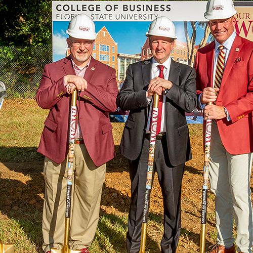 photo of three men in construction hats leaning on shovels and smiling