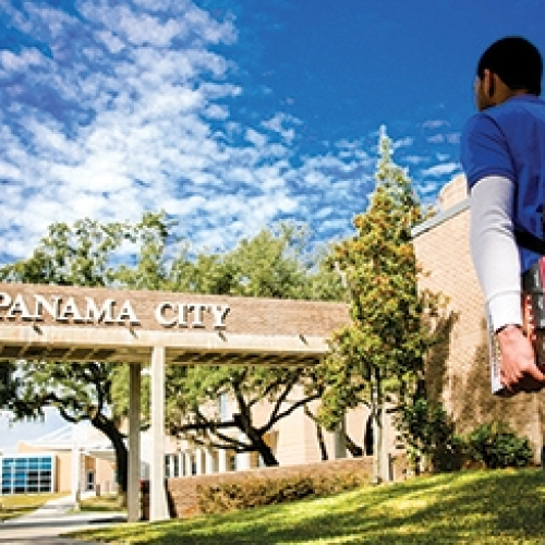 student walking onto FSU Panama City's campus with books in hand