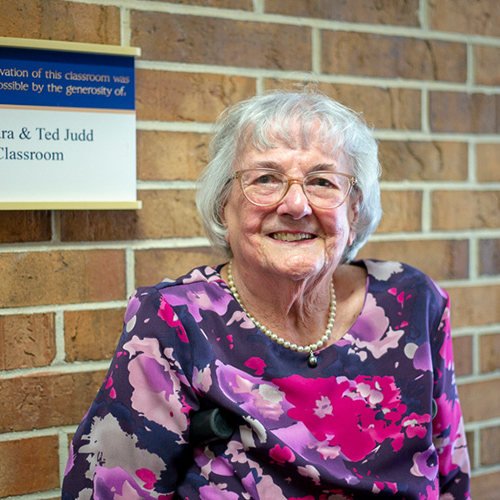 Barbara Judd in front of the Barbara and Ted Judd Theatre Classroom at Tallahassee Community College.